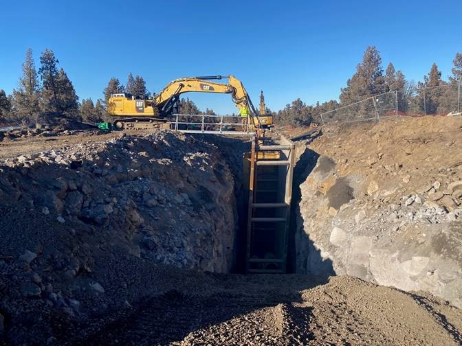 A photo of work crews and large excavation equipment installing pipe in a large trench at Juniper Ridge.