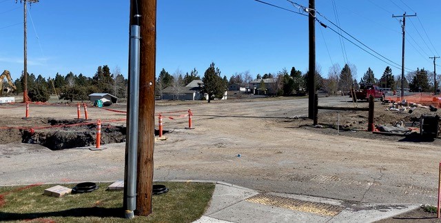 A photo of the Eagle/Cole Roundabout construction site. There is a cone barricade around an excavated trench and construction equipment and a truck parked on site.