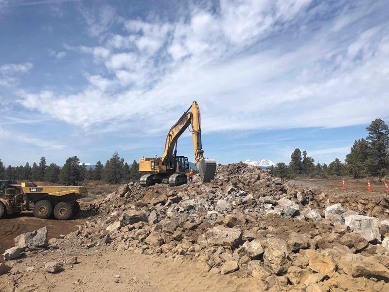 A photo of work crews using large excavation equipment to remove a blast hump.