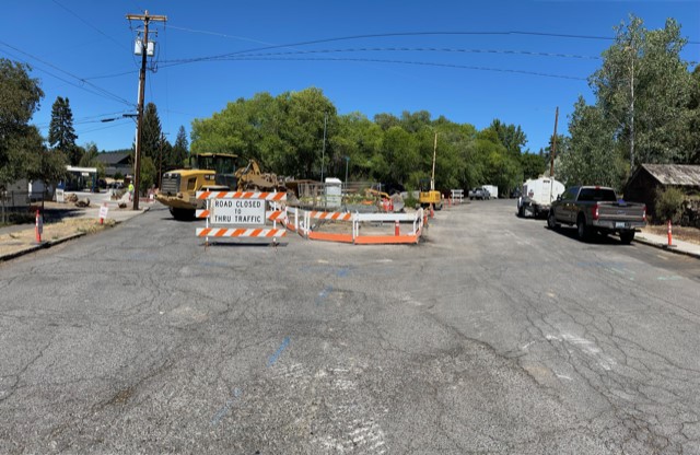 A photo of work crews and equipment working in the NW Riverside Blvd closure. There are cones and a barricade surrounding the work site.