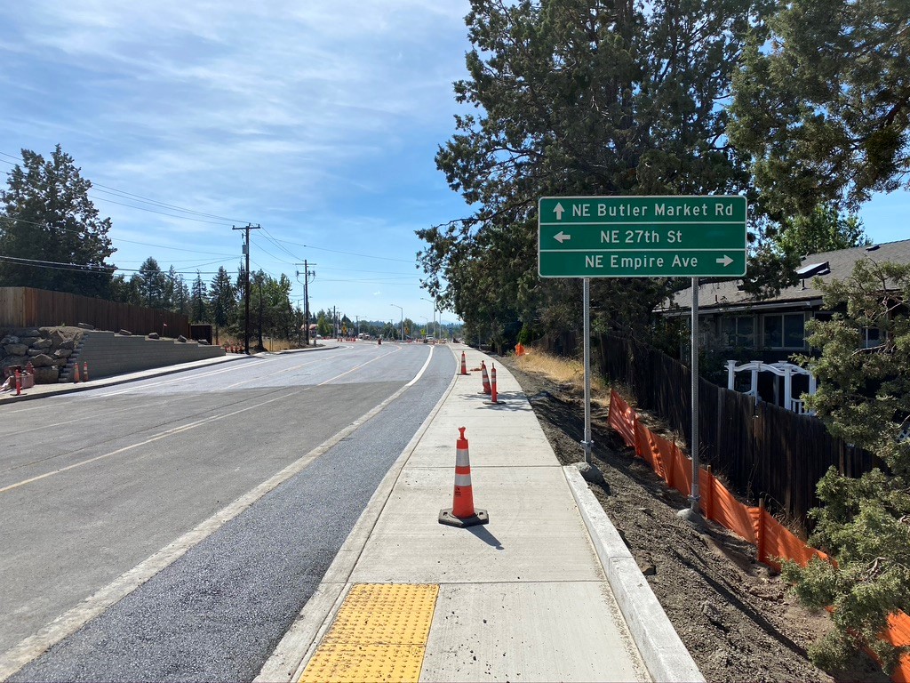 A photo of Butler Market Road near the 27th Street roundabout. There are cones set up on the sidewalk along the road.
