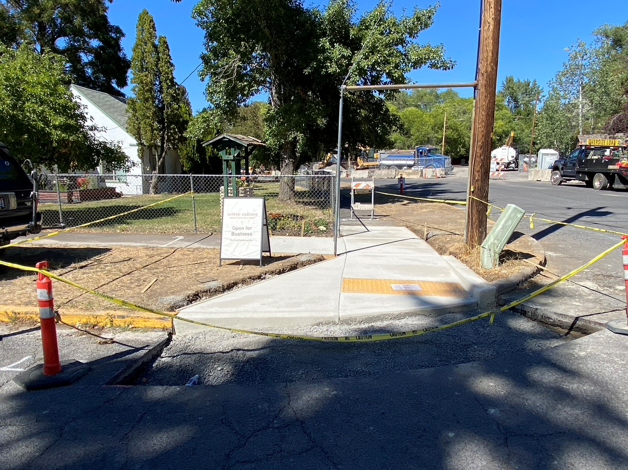 A photo of a newly installed ADA ramp surrounded with cones, caution tape, and a sidewalk barricade.