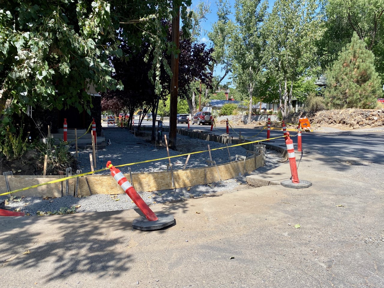 A photo of preperations being made for a new ADA ramp to be installed. There is a wooden form set for the concrete work and cones, caution tape, and a sidewalk barricade are surrounding the work site.