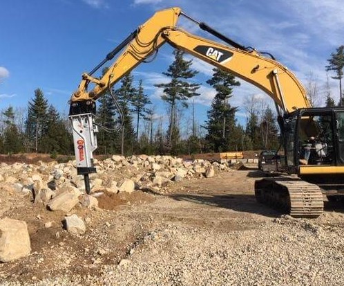 A photo of an excavator hammer breaking up rocks in preparation for excavation work.