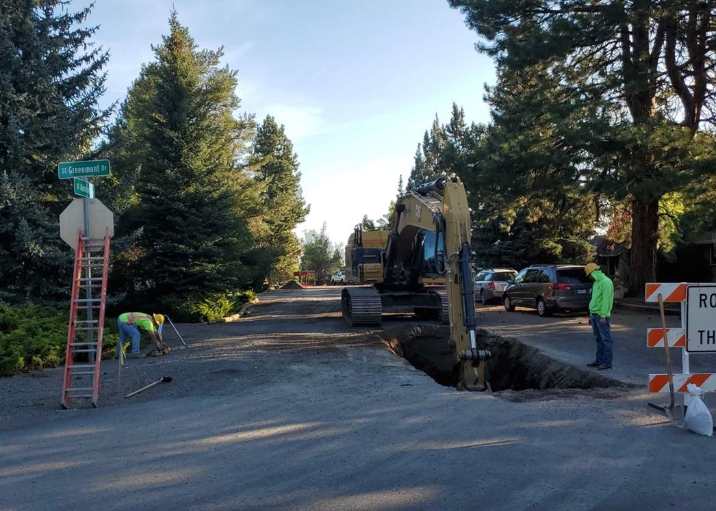 A photo of work crews and an excavator performing trench work for the sewer main installation on Admiral Way at Greenmont Drive.