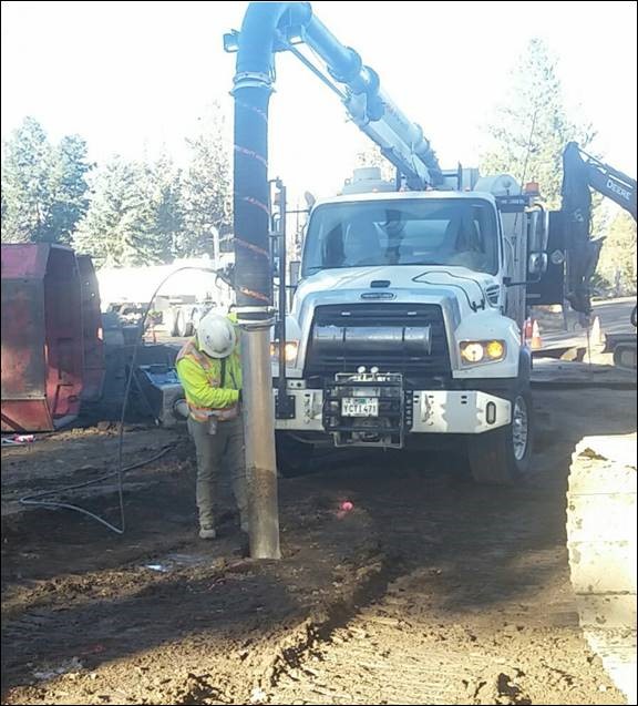 A photo of a work crew member using a vacuum truck to perform potholing.