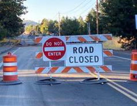 A photo a barricade, cones, and road signs marking the road closure, do not enter.