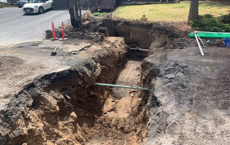 A photo showing a lateral trench excavation. There are pipes exposed in the trench.