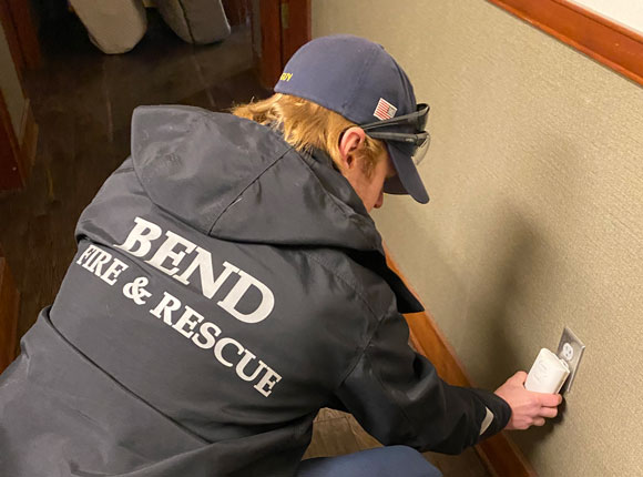 Bend Fire and Rescue employee checking a carbon monoxide alarm.