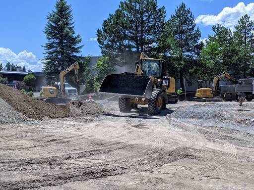 An aerial photo overlooking work crews and equipment grading the southwest corner of Simpson and Columbia for the new sidewalk.