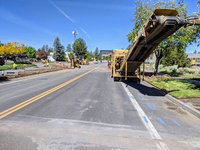 A photo of work crews and asphalt removal equipment.