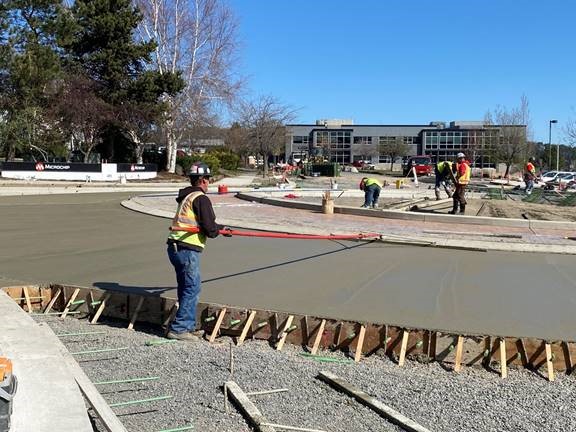 A photo of work crews performing concrete finising work around the roundabout.