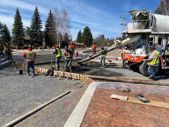 A photo of work crews pouring concrete in the roundabout travel lanes.