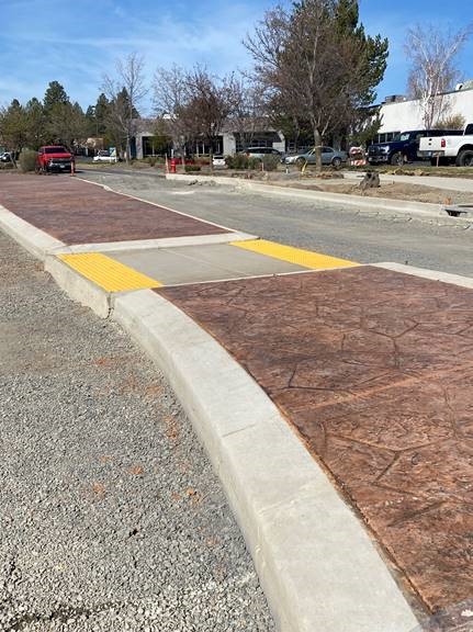 A photo of a traffic island with stamped concrete and a crosswalk.