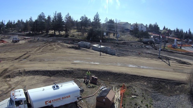 A photo showing work cres, vehicles, and a water truck hooked up to fill at the Butler Market Rd & 27th St roundabout construction site.