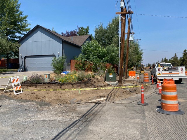 A photo of NE Purcell Blvd and NE Purser Lane. There is cones, caution tape, and signs setup along the shoulder of the street.