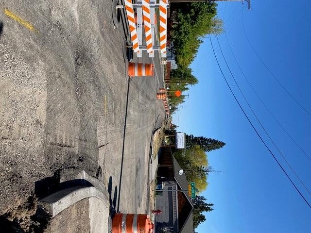 A photo of NE Purcell Blvd. facing north. There are barricades, cones, and signage setup along the street.