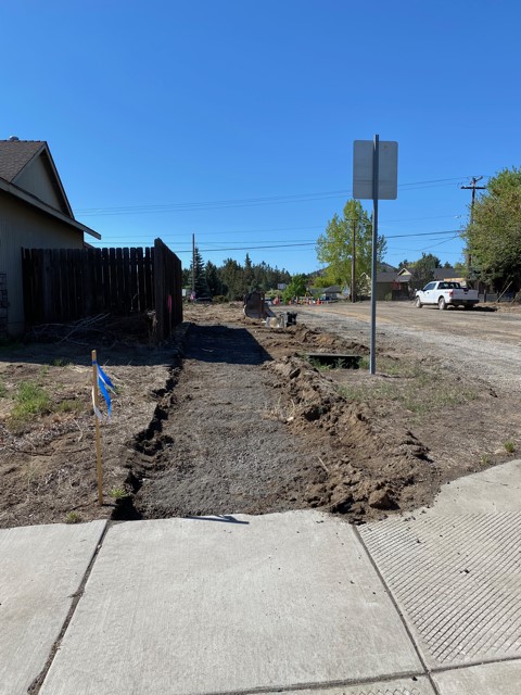 A photo of NE Purcell facing south. The paved street and a section of sidewalk has been cleared.