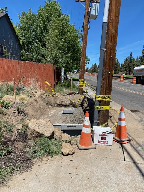 A photo of the Pacific Power utility work being constructed at the intersection of NE Purser Ln. and NE Purcell Blvd. There are cones and yellow caution tape around the project site.