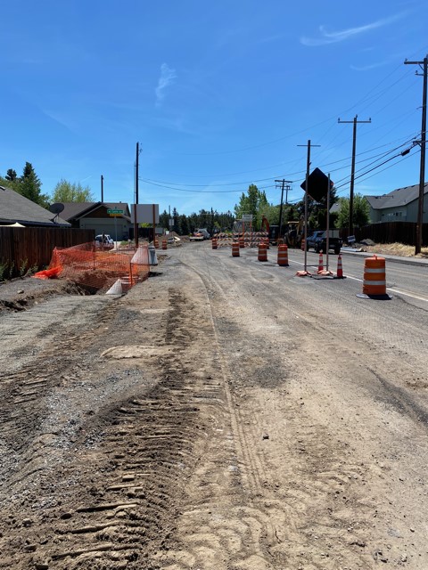 A photo of the storm sewer maintenance holes and sidewalk improvements being built along NE Purcell Blvd. There are cones, barricades, and signage along the street.