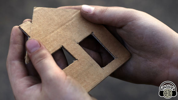 hands holding a cardboard house.