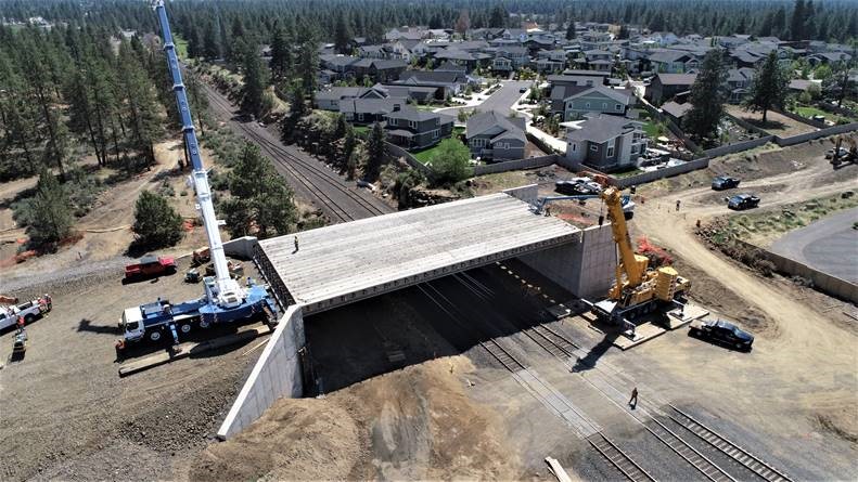An aerial photo of the BNSF railroad tracks looking southwest at the new bridge. There are two cranes at the project site.