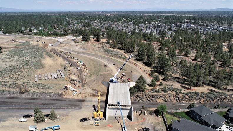An aerial photo of the new bridge looking east. There are two cranes at the project site.