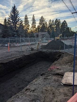 A photo of the completed excavation for the north storm water planter. Cones and a chain link fence surround the excavation site.