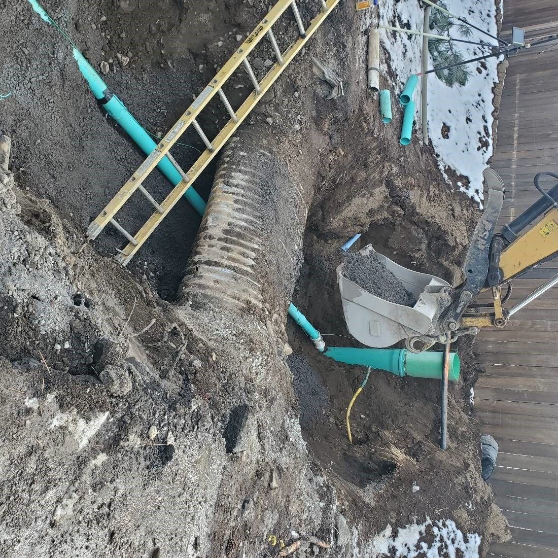 A picture of work crews excavating in a trench to install the new sewer main and service connections, while working around an existing storm main.