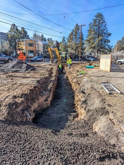 A photo overlooking a trench while work crews and excavation equipment install stormwater lines at the corner of 12th Street and Newport Avenue.