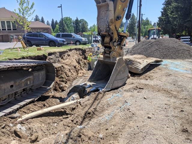 A photo of work crews using excavation equipment to remove the old stormwater pipe and prepping the trench for the new pipe installation.