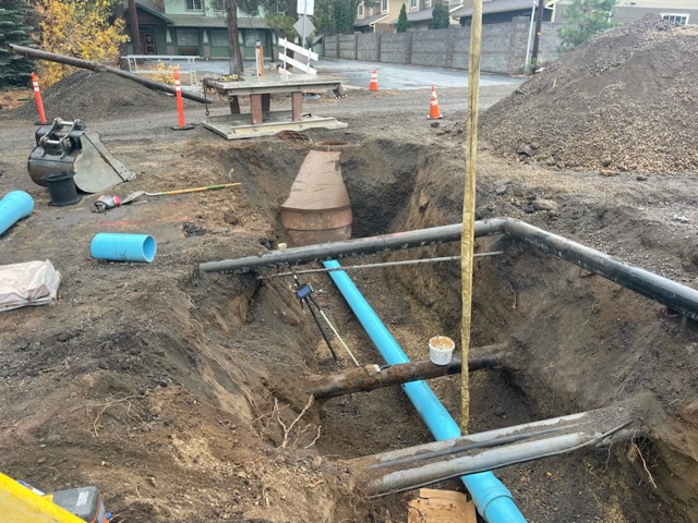 A photo looking over a trench at the excavation and waterline construction on Newport Ave.