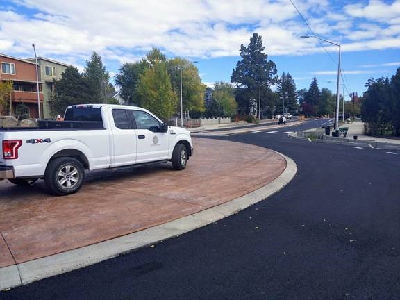 A photo of Segment 1 at the 9th Street roundabout. A city of Bend truck is parked on the truck apron of the roundabout.
