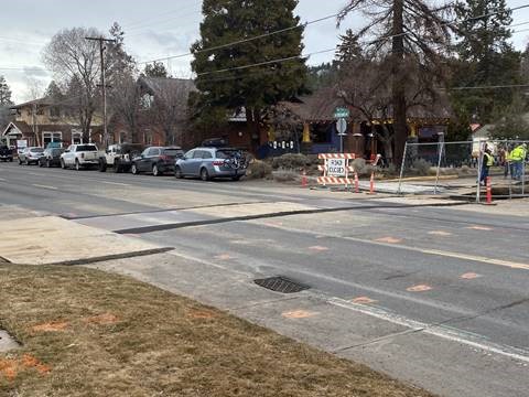 A photo of NW Newport Avenue and work crews working behind the barricade and closure signage on NW 10th Street.