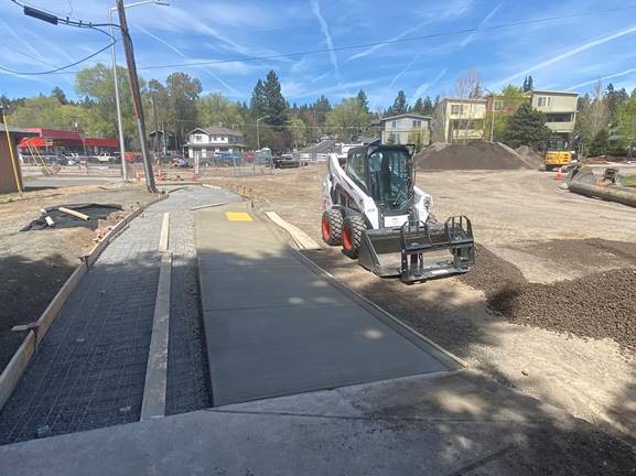A photo of the project work site, equipment, and concrete work being done.