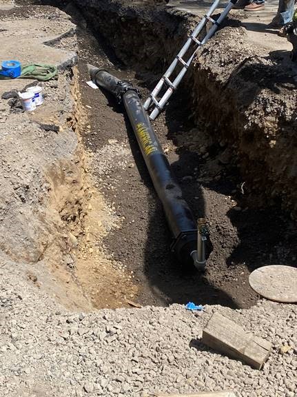 A photo of the watermain line being installed in an open trench.