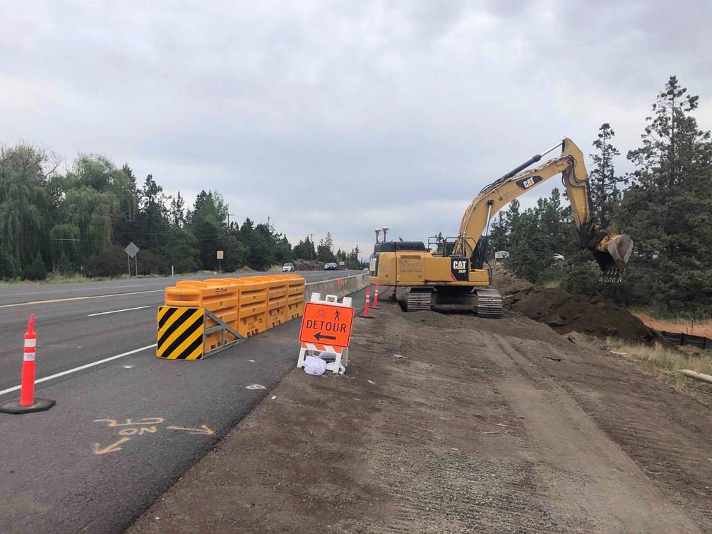 A photo of work crews using large excavation equipment to perform pre-hammering efforts on the shoulder of OR Hwy 97.