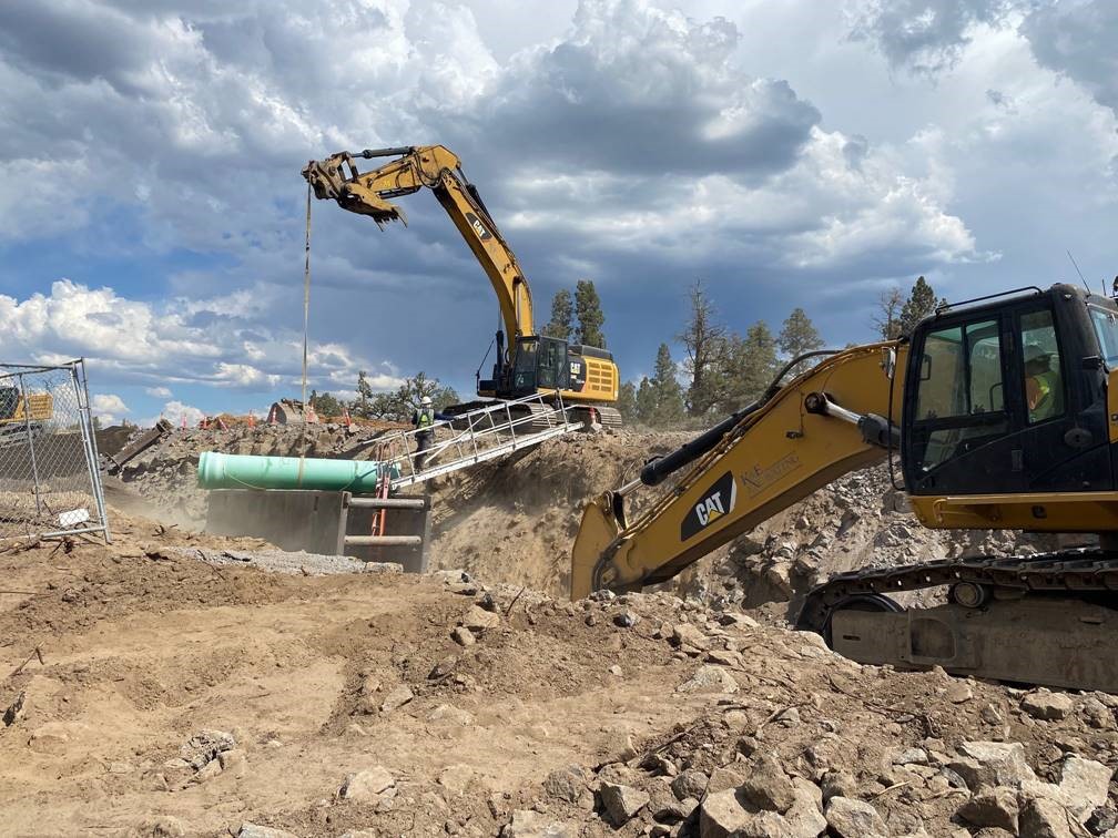 A photo of work crews and large equipment installing pipe at Juniper Ridge.