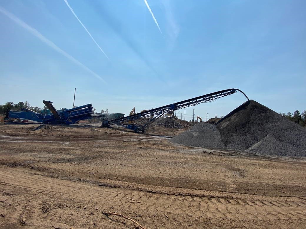 A photo of the rock crusher site, crushing rocks and producing a large mound of gravel.