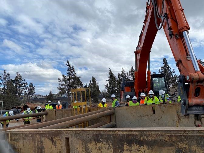 A photo project members and City Council wearing safety vests and hard hats and visiting the OR 97 crossing project site.