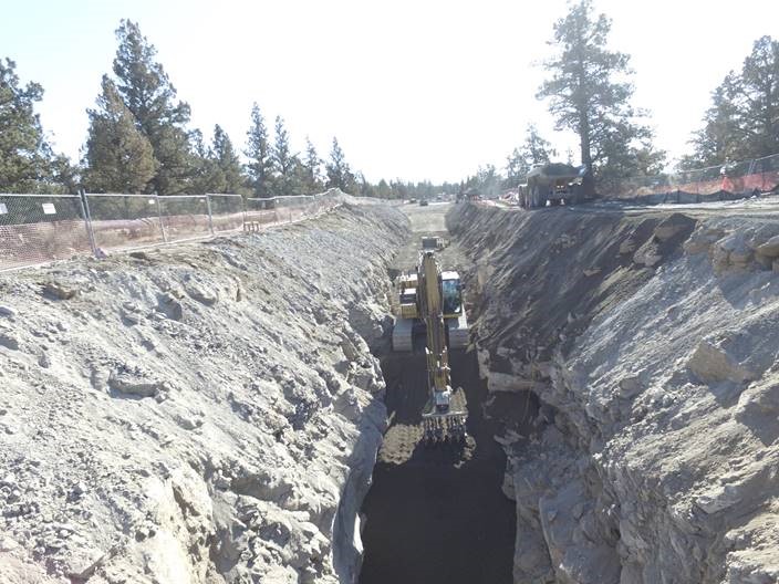 A photo of large excavation equipment performing a pipe trench backfill.