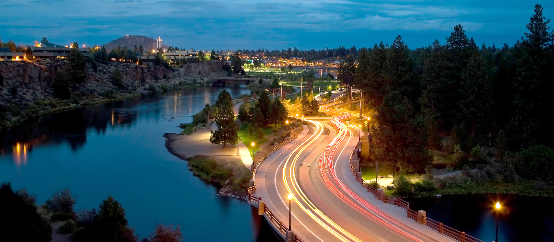 Trails of light from cars as they pass over Reed Market Bridge at night.