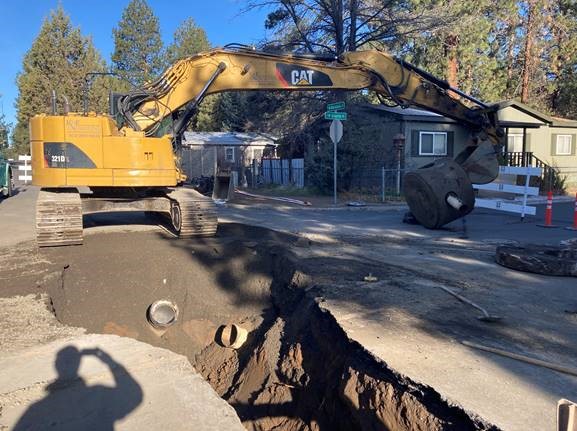 A photo of work crews using an excavator to remove the existing maintenance hole at the Mahogany/Granite intersection.