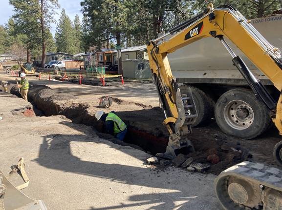 A photo of work crews and excavation equipment excavating a trench for the removal of the existing pressure sewer force main in McMullin Drive.