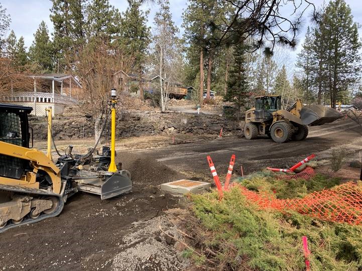 A photo of the new catch basin on Cinder Lane. Work crews are using a wheel loader and a compact track loader to grade along Cinder Lane.