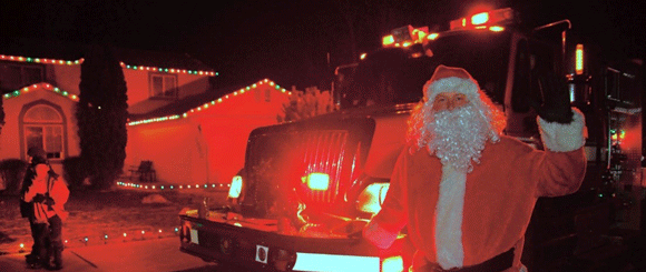 Santa Claus in front of a fire truck.