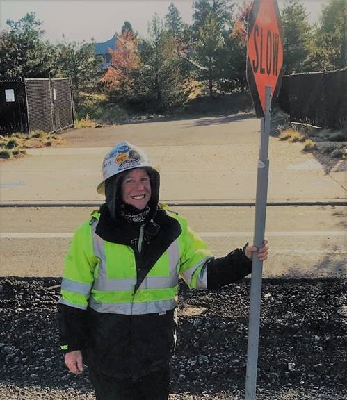 Picture of Sheila Hart smiling and holding a traffic control sign.
