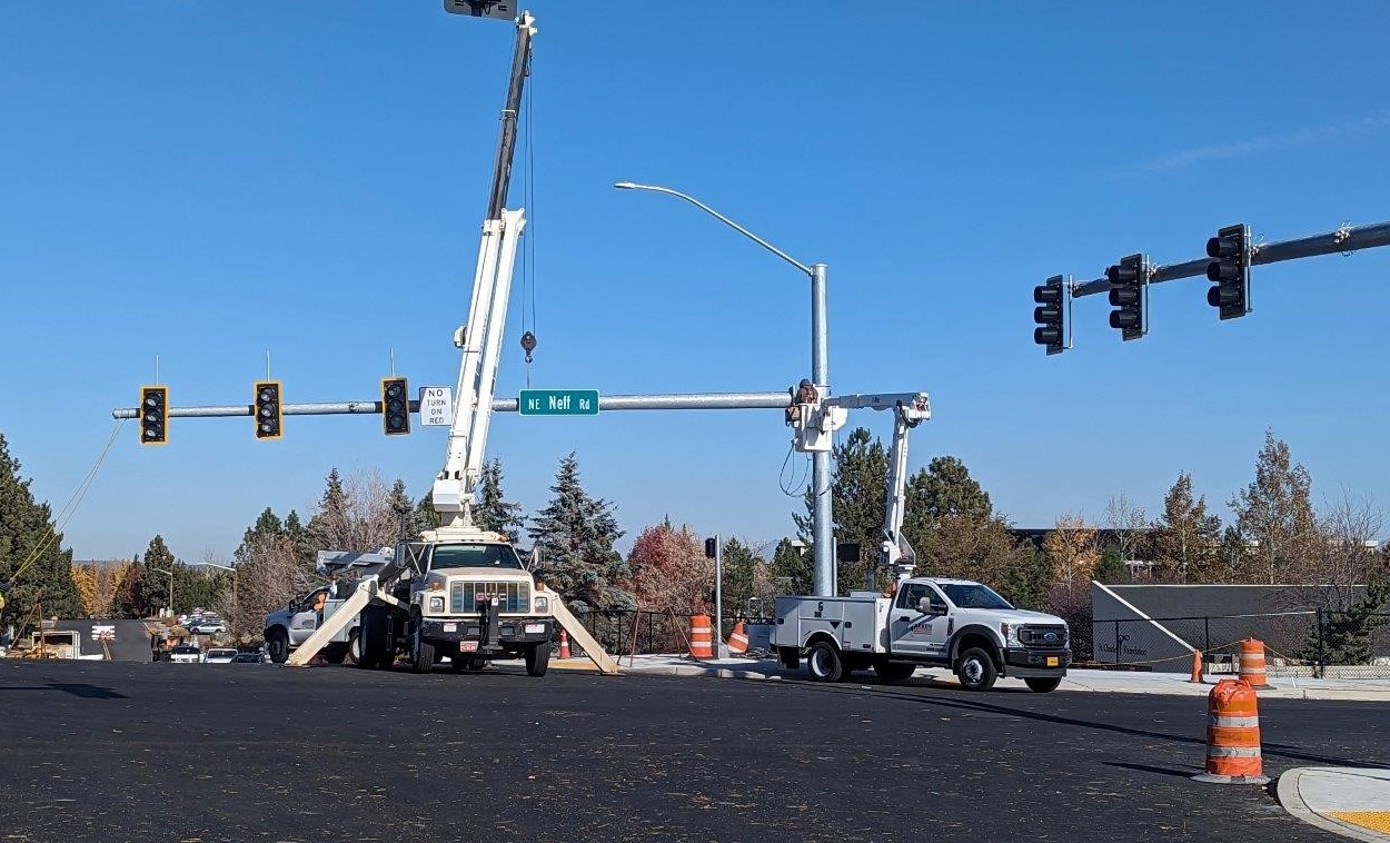 crane and workers installing signal and street lighting pole and mast