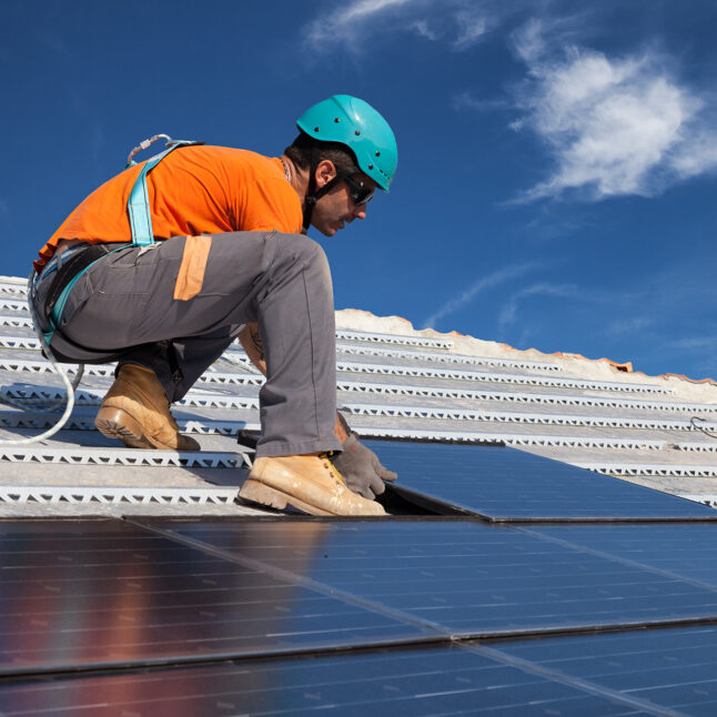 Man installing solar panels on a rooftop.
