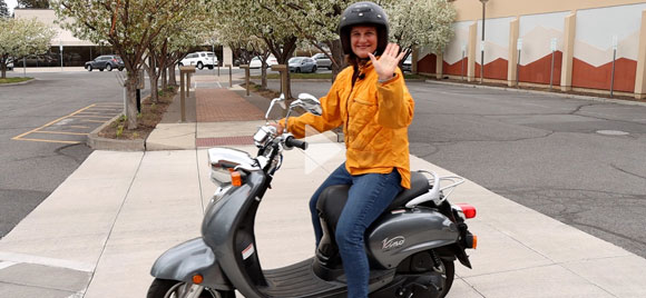 Mayor Sally Russell on a scooter waving.